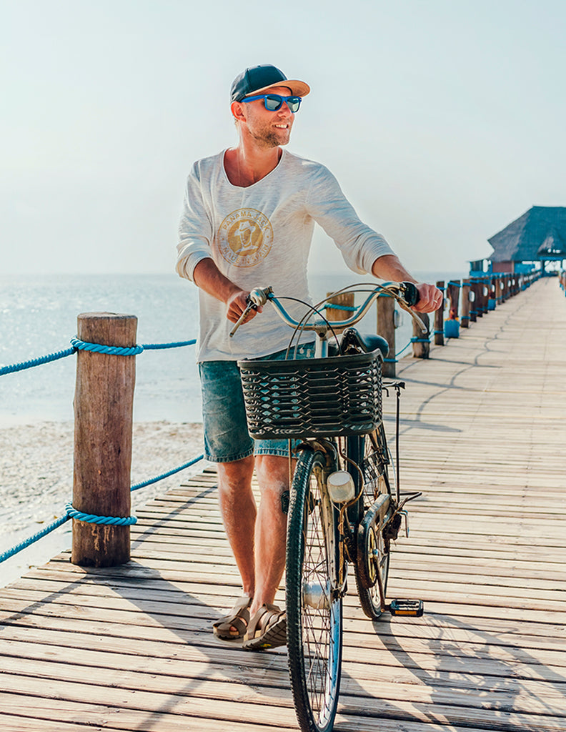 Chico paseando en bicicleta por una pasarela de playa con el mar de fondo